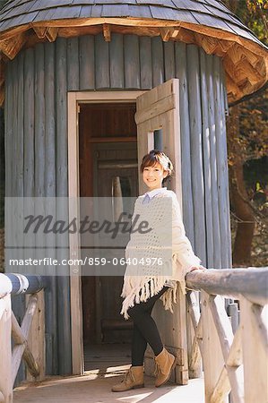 Japanische Frau in einer weißen Strickjacke gelehnt eine Holztüre