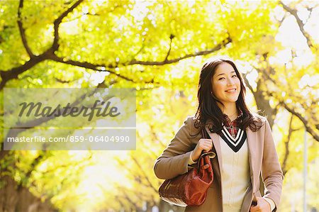 Femme japonaise avec de longs cheveux regardant la caméra avec des feuilles jaunes en arrière-plan