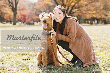 Japanese woman with long hair and a dog in a park looking at camera