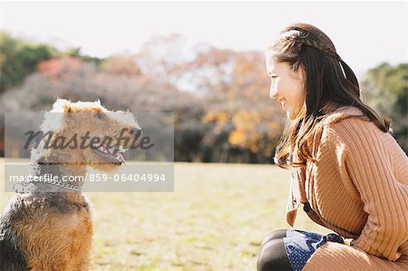 Japanische Frau mit langen Haaren und ein Hund in einem Park, Blick auf einander