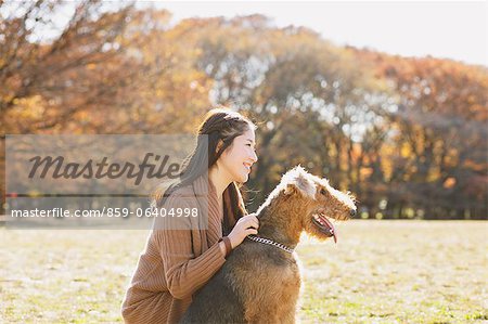 Japanische Frau mit langen Haaren und einem Hund in einem Park, Wegsehen
