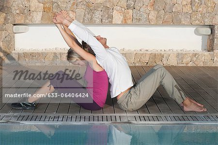 Salon de la jeune couple dos à dos à bord de la piscine qui s'étend