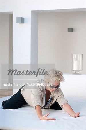 Reife Frau kniend auf dem Bett im Freien, nach vorne lehnen