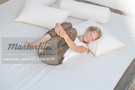 Jeune femme reposante sur le lit en position fœtale