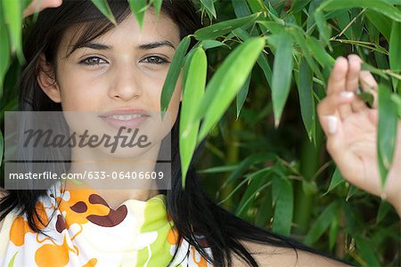 Young woman smiling amongst bamboo foliage, portrait