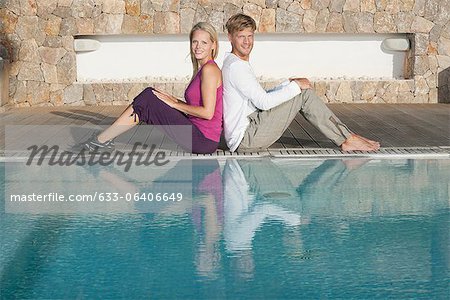 Séance de jeune couple dos à dos au bord de la piscine, portrait