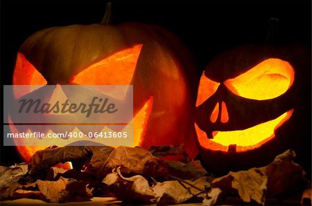 Halloween pumpkins over dried leaves on dark background