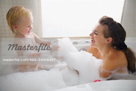 Mère et bébé jouer avec de la mousse dans la baignoire