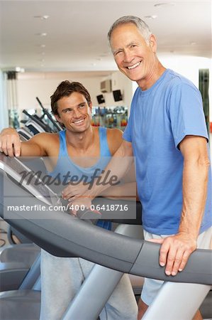 Mann arbeitet mit Personal Trainer zum Ausführen der Maschine im Fitness-Studio