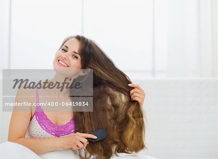 Smiling young woman brushing hair