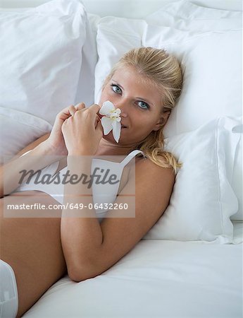 Woman smelling flower on bed