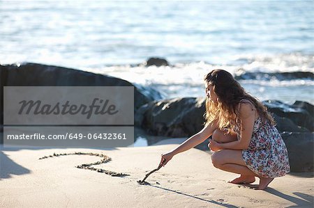 Femme dessin point d'interrogation dans le sable