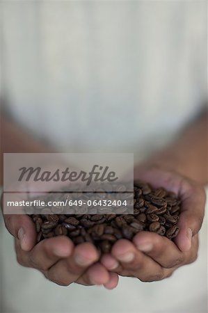 Close up of hands holding coffee beans