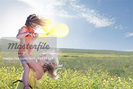 Sisters playing in field of flowers