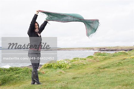 Woman playing with scarf in grassy field