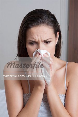 Femme soufflant son nez sur lit