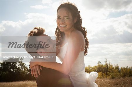 Newlywed groom holding bride outdoors