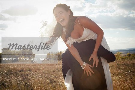 Newlywed groom carrying bride outdoors