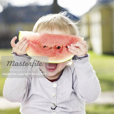 Fille d'enfant en bas âge jouant avec melon d'eau