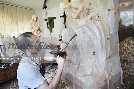 Sculptor chiseling figure from wood