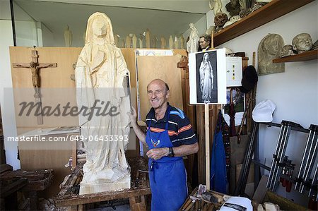 Sculptor standing with wood figure