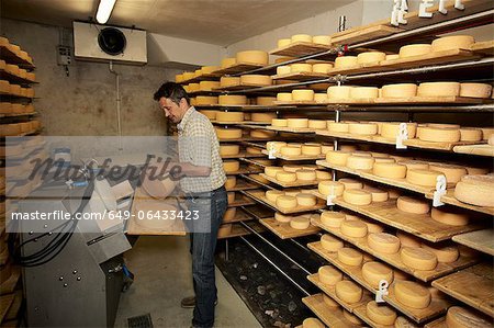 Worker finishing wheel of cheese in shop