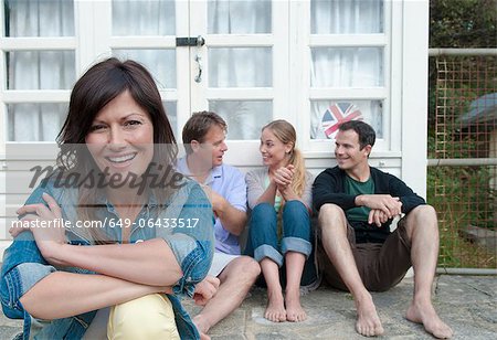 Femme assise avec la famille à l'extérieur de la maison