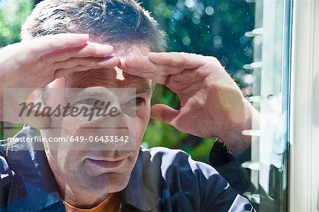 Homme regardant dans la fenêtre de la maison