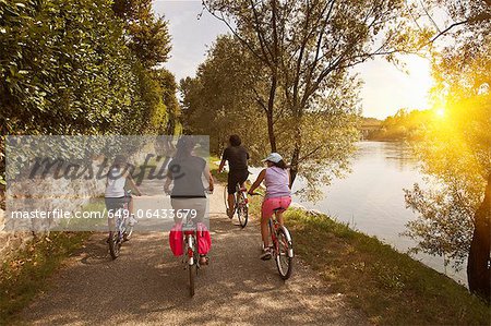 Family riding bicycles by river bank Family riding bicycles by river bank
