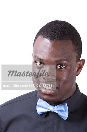 Portrait of happy young African American man in bow tie against white background