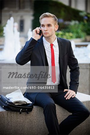 Jeune homme assis sur la plateforme pendant l'utilisation de téléphone cellulaire