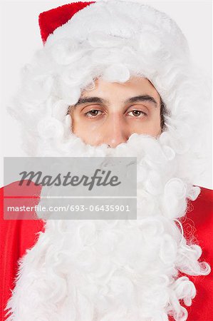 Portrait of young man in Santa costume against gray background