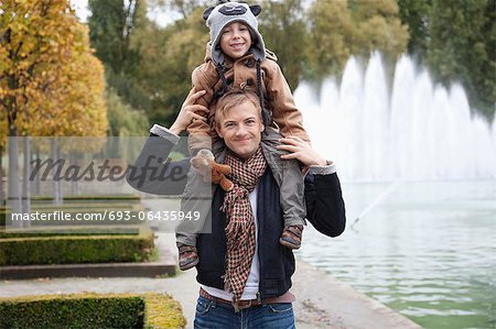 Portrait of father carrying son on his shoulders at park