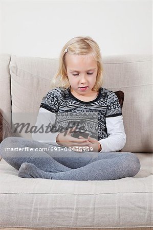 Young girl reading text message on sofa