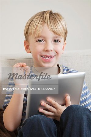 Young boy with digital tablet gesturing OK