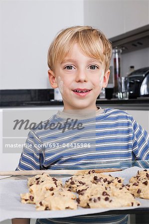 Portrait d'heureux jeune garçon en face de la plaque à gâteaux de cookies