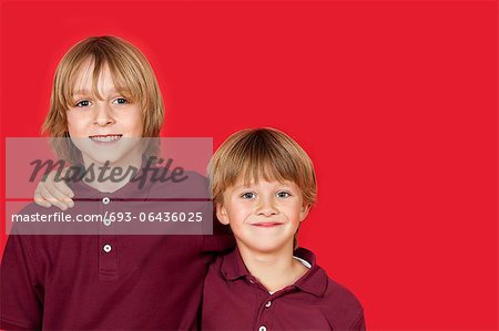 Portrait of two happy brothers against red background