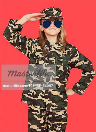 Porträt von jungen Mädchen in Militäruniform salutieren vor rotem Hintergrund