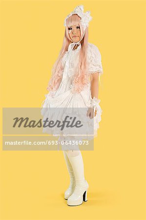 Portrait de pleine longueur de la jeune femme habillée comme une poupée sur fond jaune