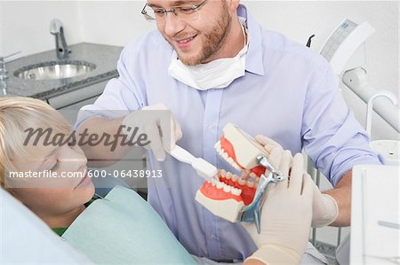 Dentist demonstrating to Boy how to Brush Teeth during Appointment, Germany