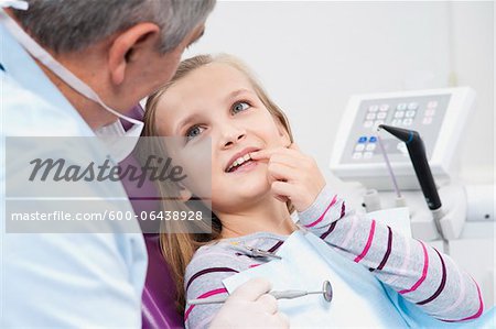 Girl Showing Tooth to Dentist during Appointment, Germany