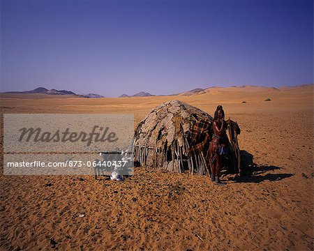 Portrait de femme Himba, debout près de cabane avec chèvres Namibie, Afrique Portrait de femme Himba, debout près de cabane avec chèvres Namibie, Afrique