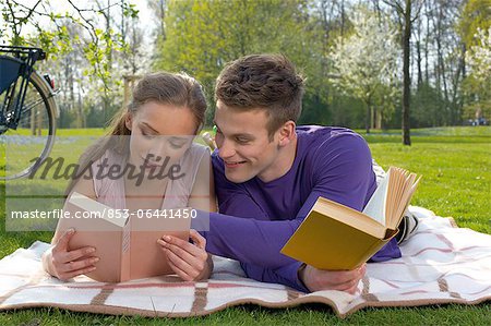 Jeune couple lisant sur un pré
