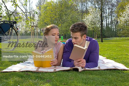 Jeune couple lisant sur un pré