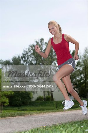 Blond young woman running on path