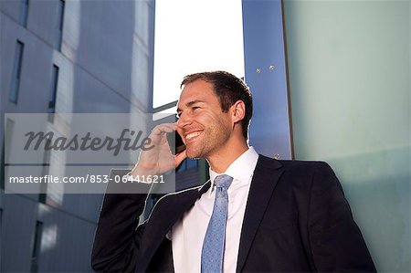 Homme d'affaires sur téléphone cellulaire à l'extérieur de sourire