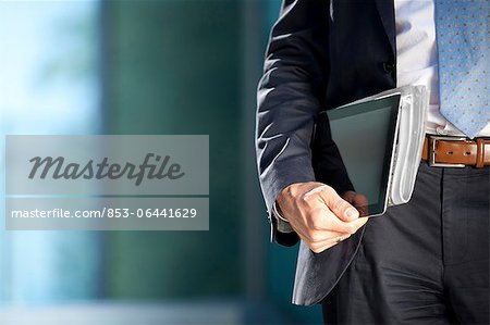 Businessman carrying tablet PC and newspaper under his arm
