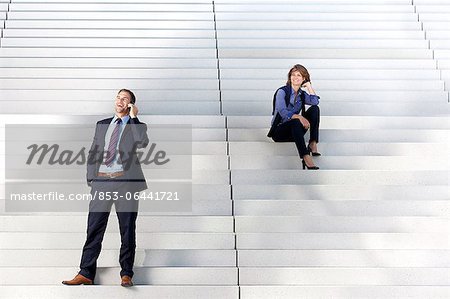 Geschäftsfrau sucht Geschäftsmann am Telefon auf Treppe