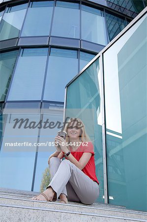 Femme blonde avec café pour aller dans les escaliers