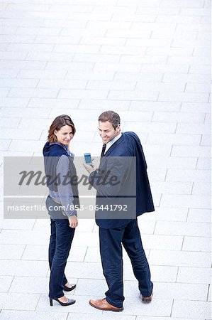 Homme d'affaires et femme d'affaires permanent avec téléphone cellulaire à l'extérieur